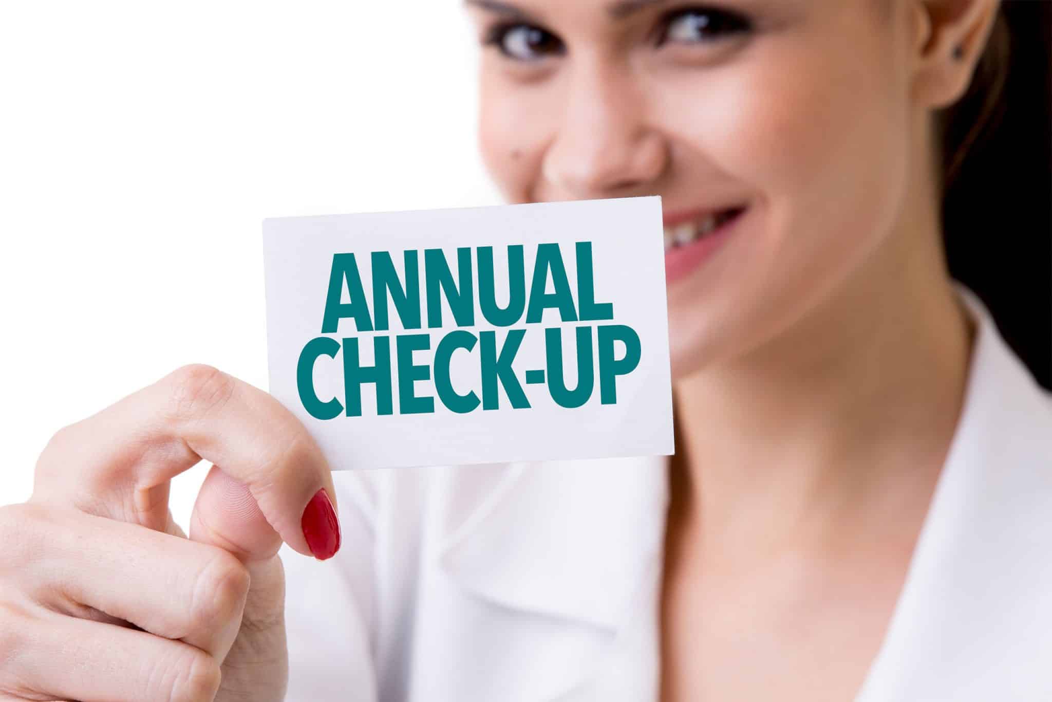 A woman holding up a card that says annual check-up.