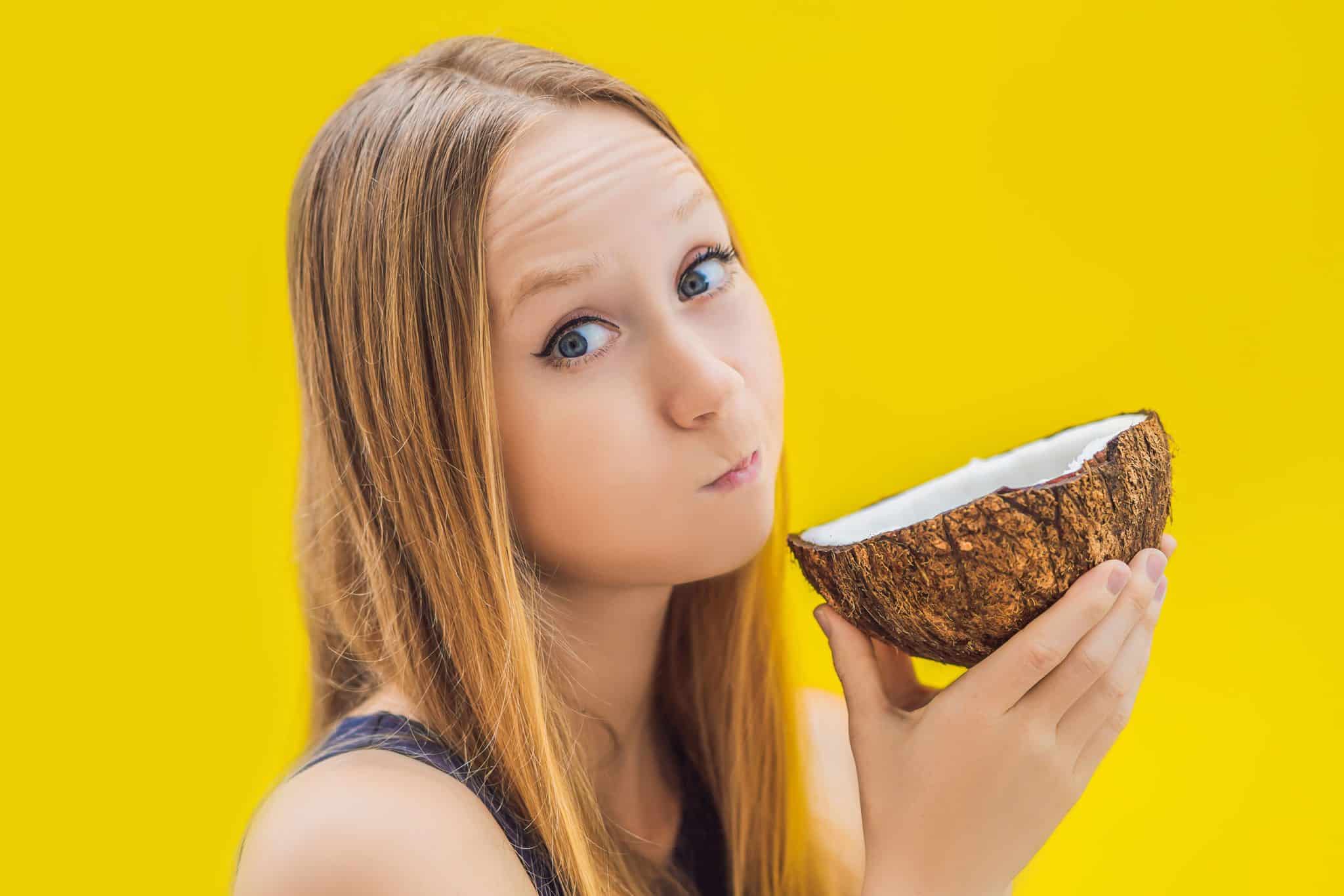 Girl depicting oil pulling while holding up a coconut