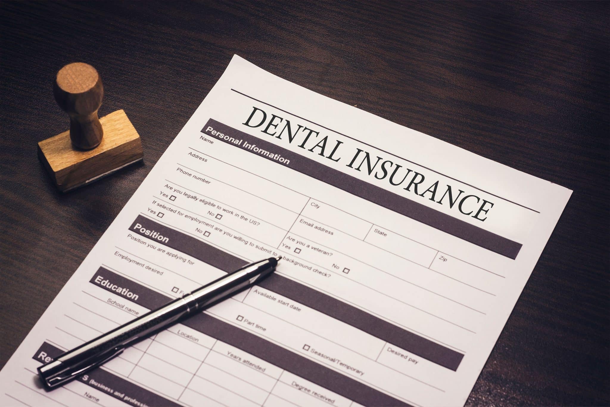 An image of a dental insurance form with a pen