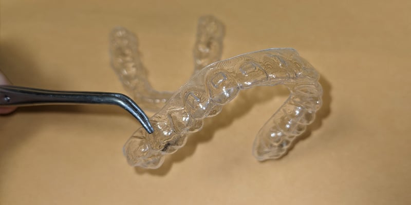 A set of clear aligners that depict the visible attachments within the aligner. They appear as rectangular indentations. These help to direct forces on the tooth to generate movement.