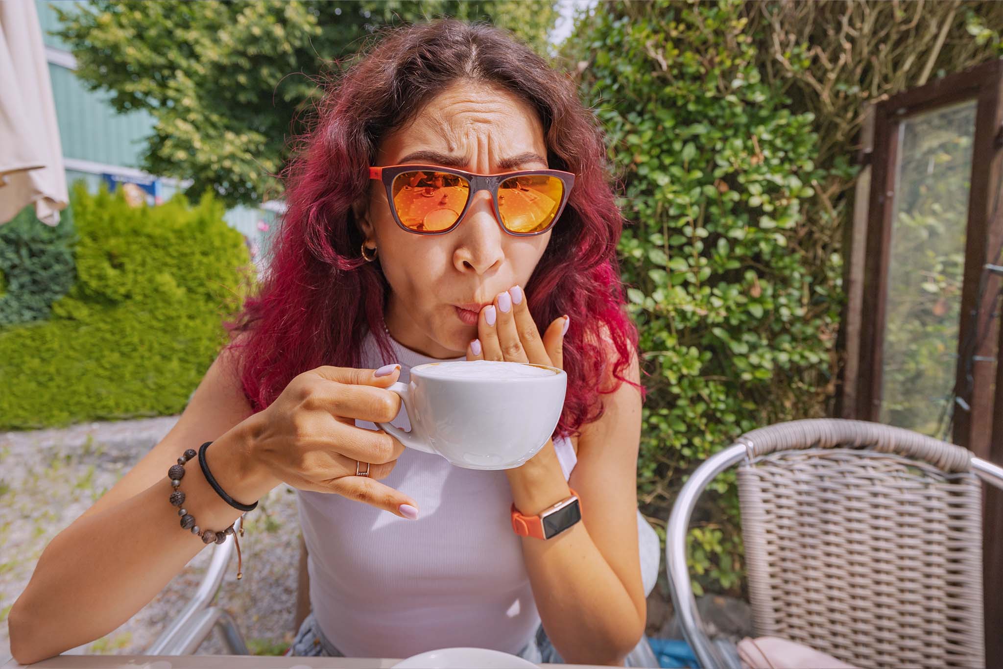 A picture of a red-haired woman who burned her mouth drinking coffee.